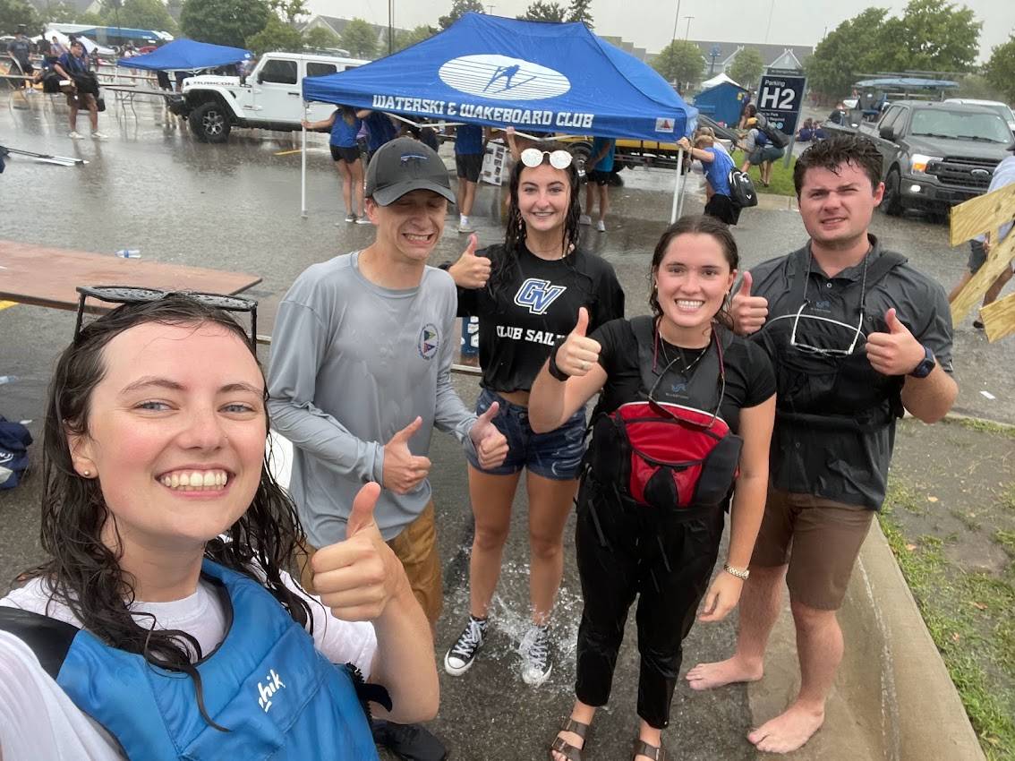 Sailing team members giving smiles and thumbs up after getting caught in a rainstorm